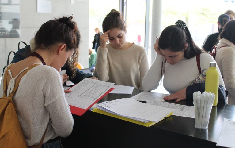 Drei junge Frauen lesen sich Informationsmaterial zur Blutspende und Blutstammzellspende durch.